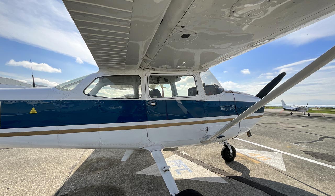 Wide-angle view from beneath the wing of a Pacific Flying Club Cessna 172 during a preflight walk-around